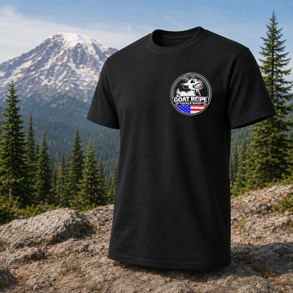 A black short-sleeve t-shirt with a circular 'GOAT ROPE' logo printed on the left chest, displayed against a scenic mountain and pine forest background.