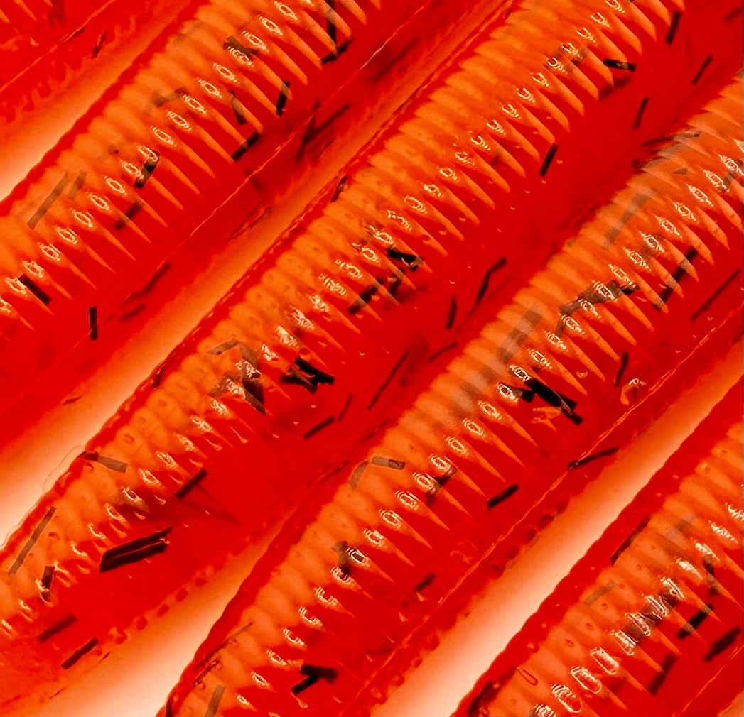Close-up of orange soft plastic with black whisker glitter on a white background