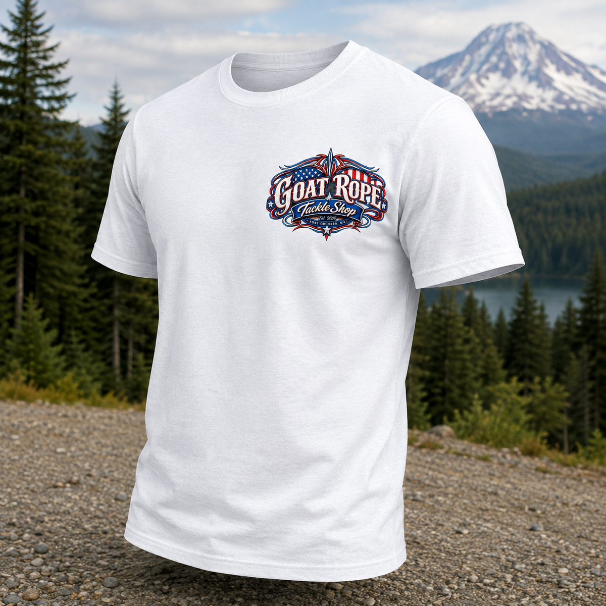 A white short-sleeve crewneck t-shirt with a 'GOAT ROPE' graphic on the chest, displayed against a blurred outdoor background of a forest, lake, and snow-capped mountain.